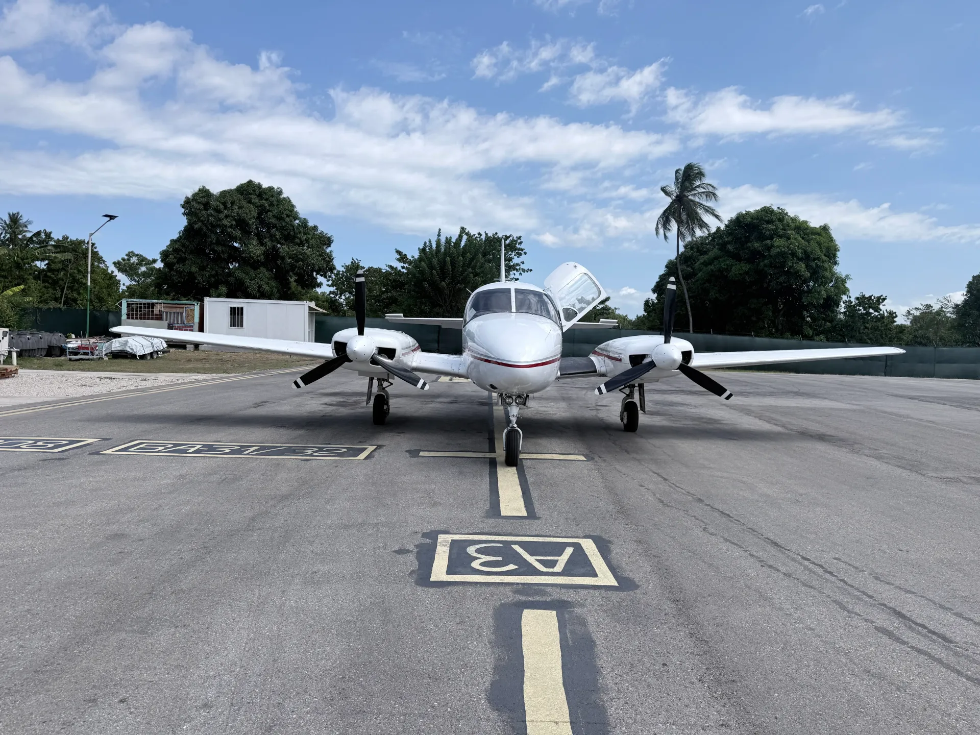 Twin-engine aircraft parked on the tarmac with its pilot door open